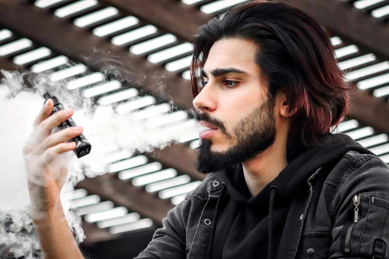 what is vaping in dubai - Portrait of a young man vaping outdoors in Dubai, showcasing modern lifestyle and fashion.